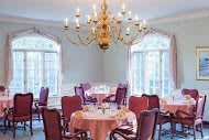 An elegant dining room with a large chandelier and multiple tables set for dining.