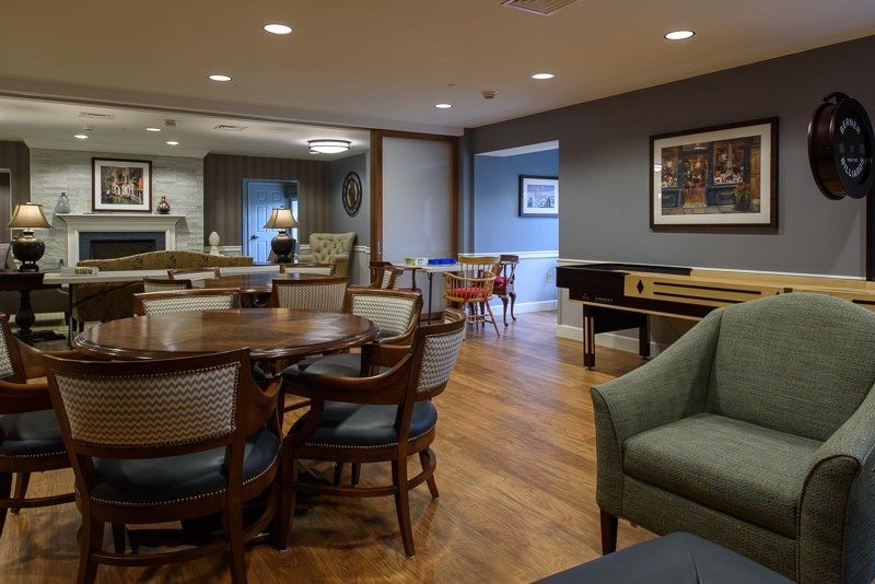 A cozy and modern living room area with tables, chairs, and a wooden floor.