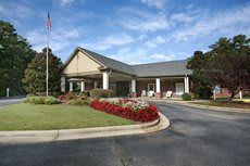 A well-maintained building entrance with a landscaped driveway and flower beds.