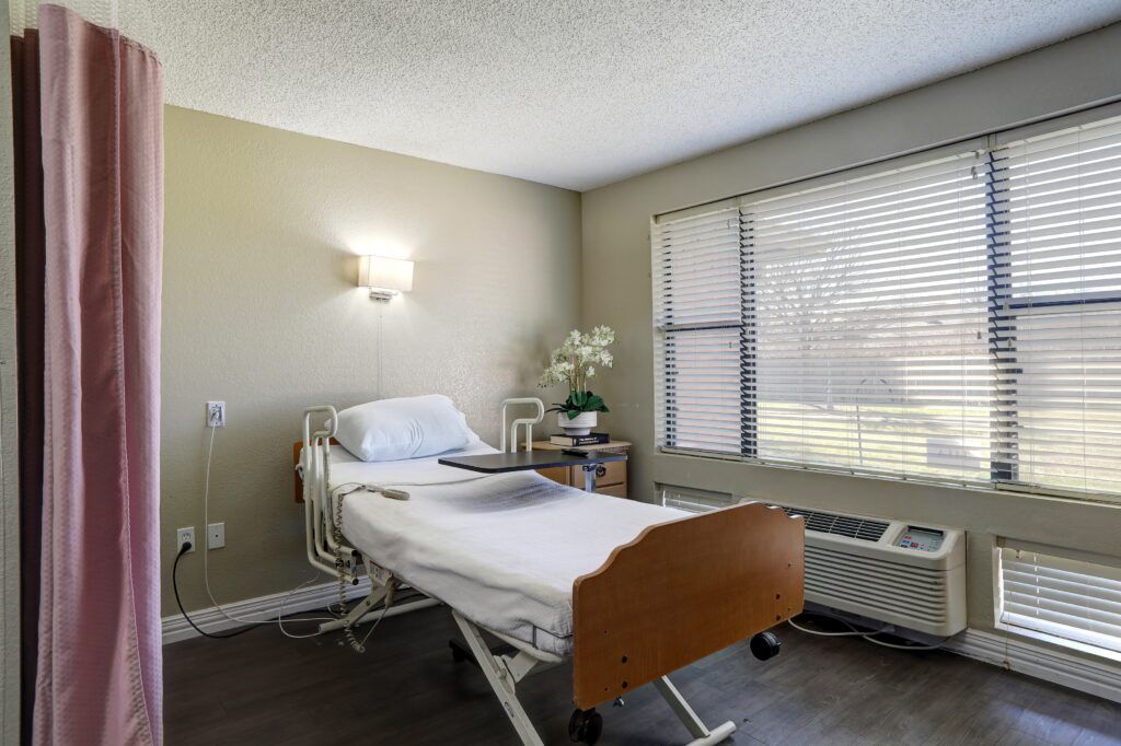 A clean and well-lit hospital room with a single bed and a large window.