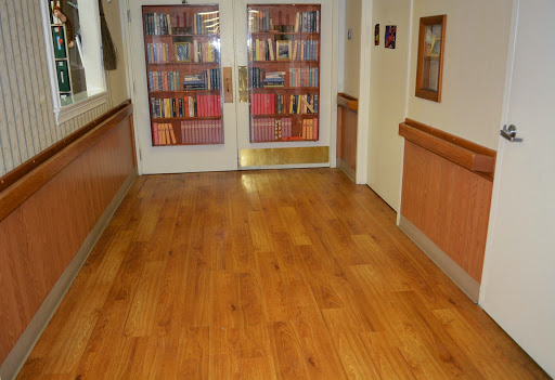 A hallway leading to a library with wooden flooring and shelves filled with books.