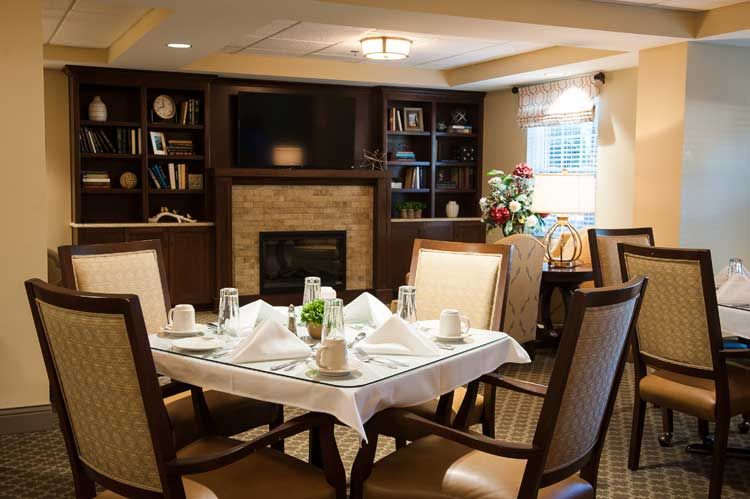 A cozy dining area featuring a neatly set table, warm lighting, and a fireplace.