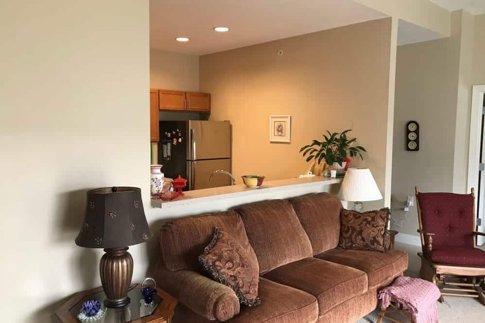 A cozy living room with a brown sofa and a view into the kitchen area.