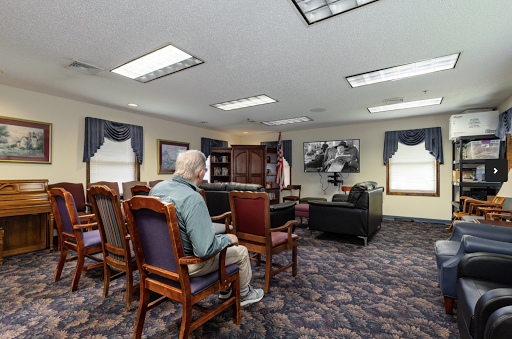 A peaceful waiting room setting, featuring an elderly person seated comfortably with a view of a television.