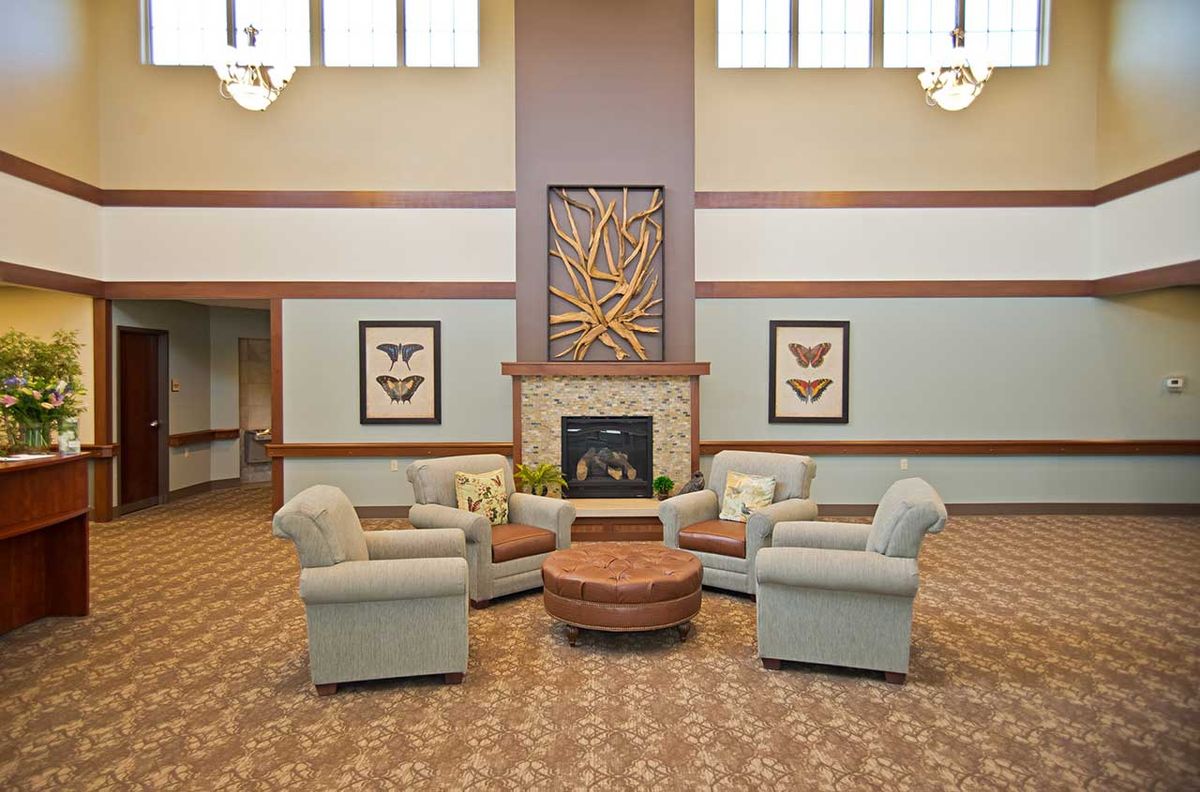 A cozy living room with a circular arrangement of armchairs and a central fireplace, decorated with framed artwork.