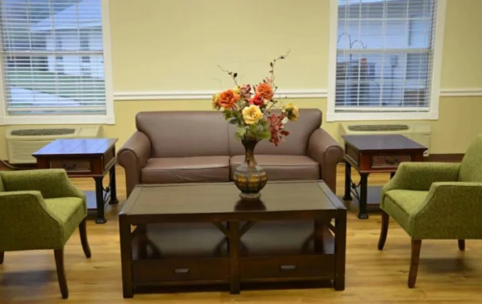 A cozy living room setup featuring a sofa and coffee table adorned with a vibrant flower arrangement.