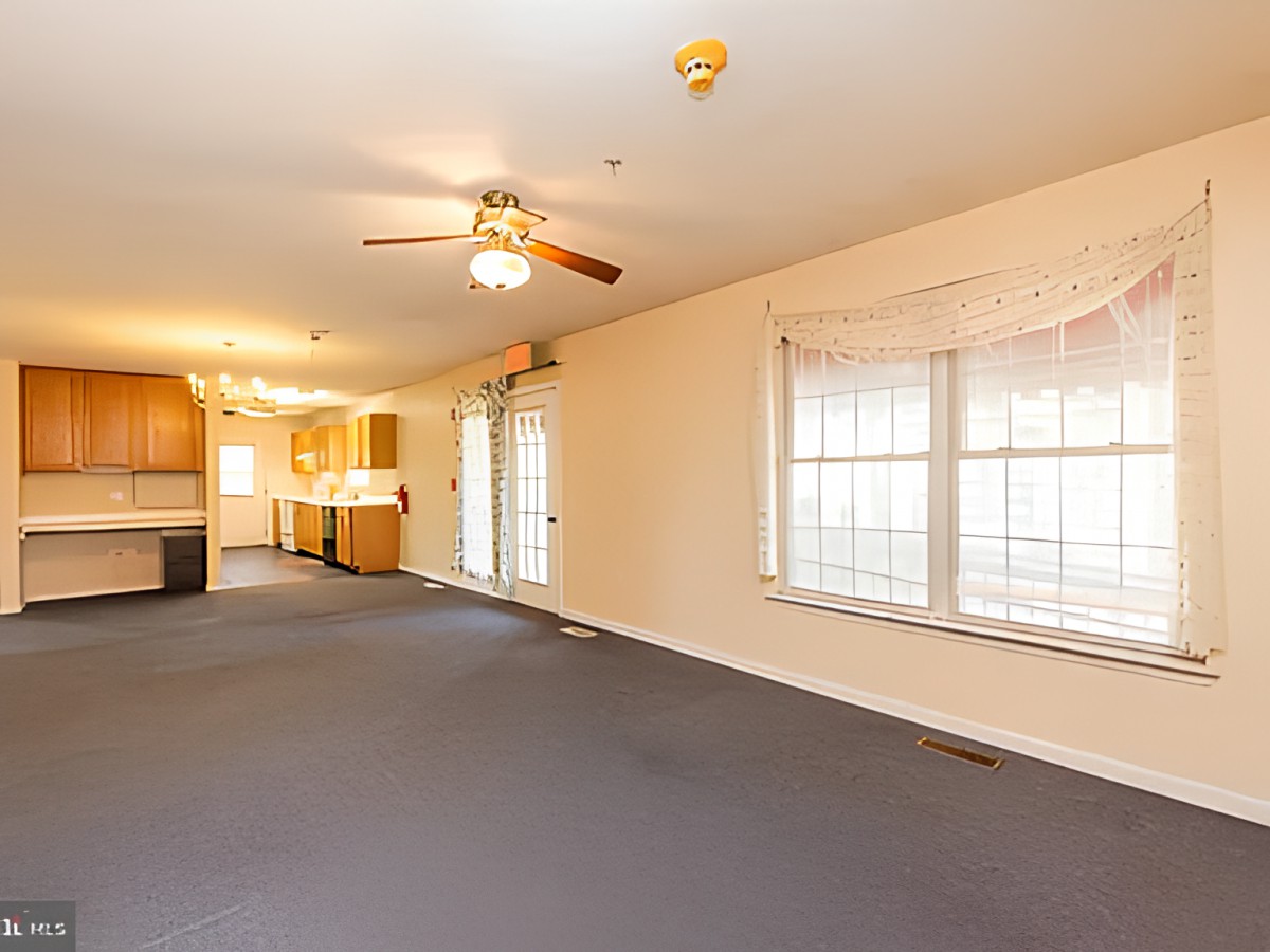An open living and kitchen area with carpet flooring and ample natural light.