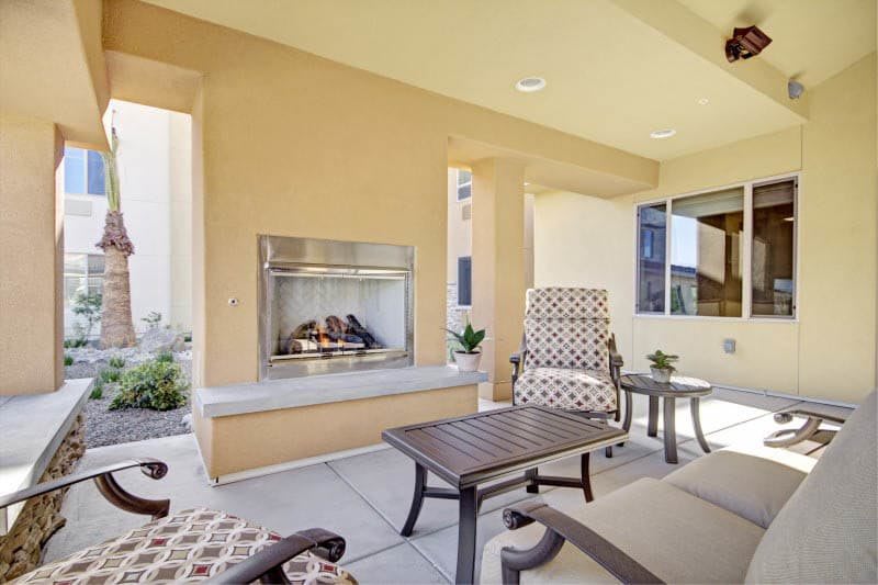A cozy outdoor patio with comfortable seating and a built-in fireplace.