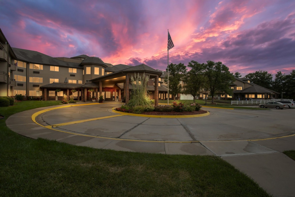 A building with a circular driveway and flagpole at sunset.