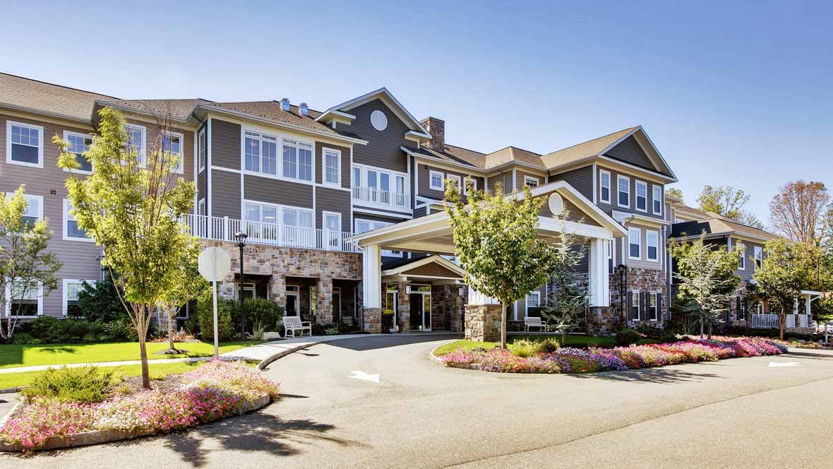 A modern residential building with well-kept landscaping under a clear blue sky.