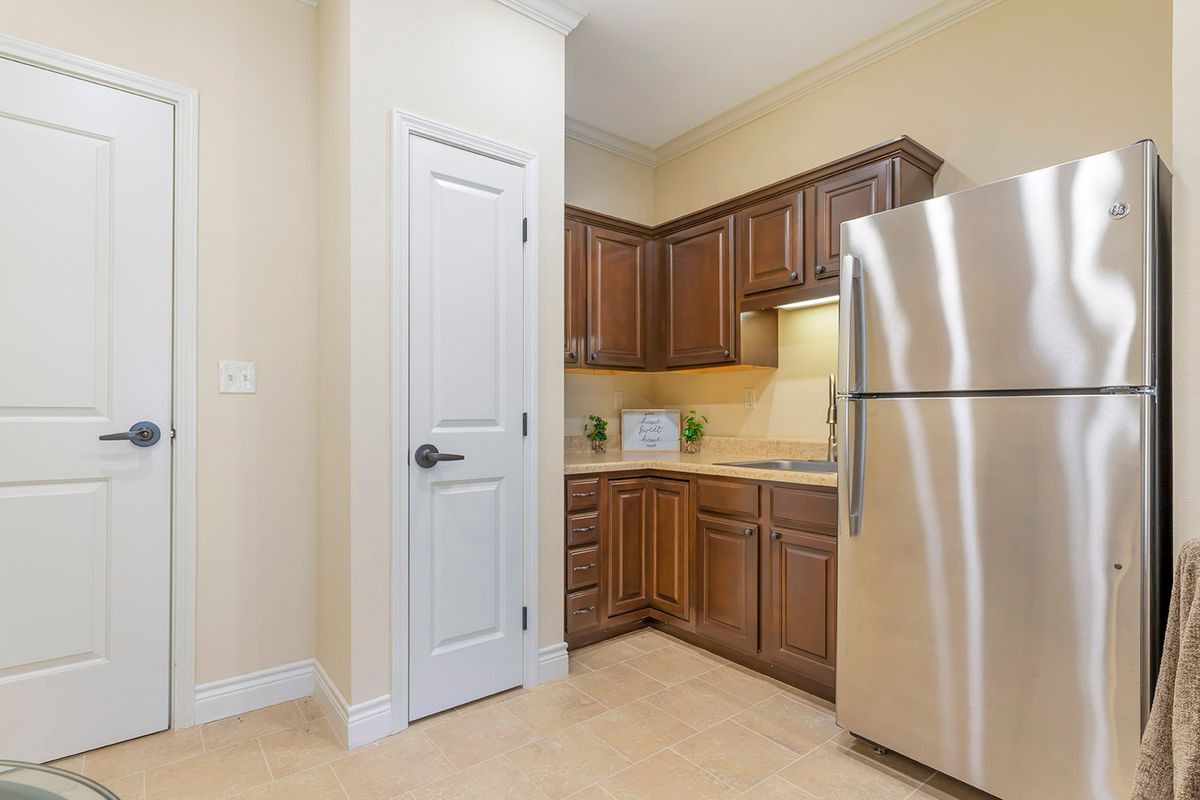 A modern kitchen with wooden cabinets and a stainless steel refrigerator.