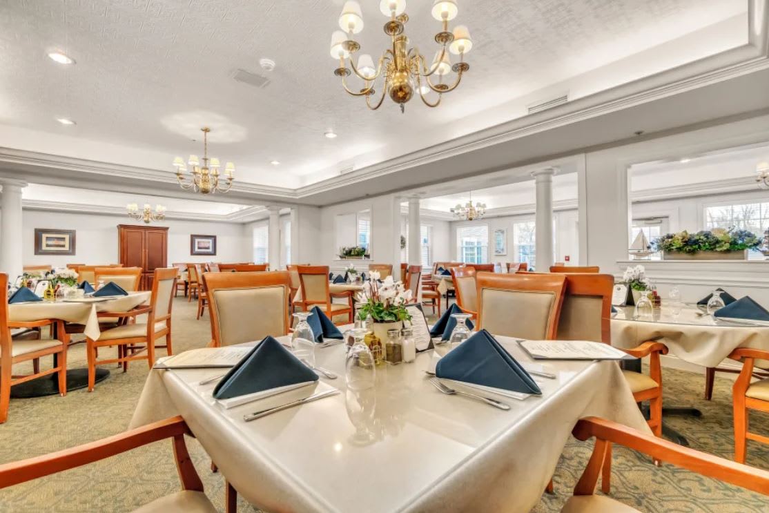 An elegant dining room with neatly set tables and chandeliers.