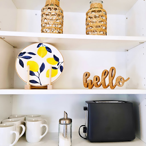 A cozy kitchen shelf arrangement featuring decorative items, a toaster, and charming ceramics.