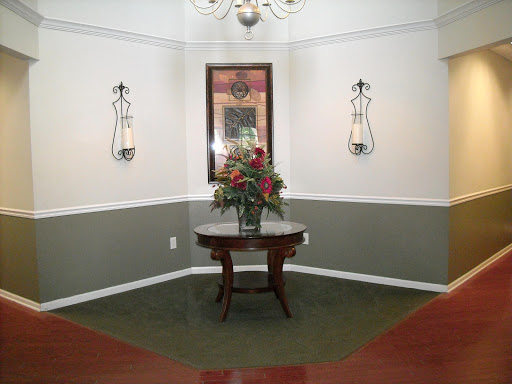 A well-decorated lobby area featuring a floral arrangement on a round table, complemented by wall sconces and a mirror.
