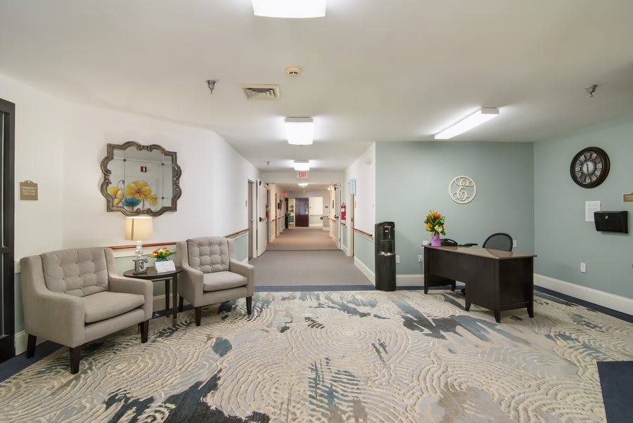 A hallway with a reception desk and seating area, featuring modern interior design elements.