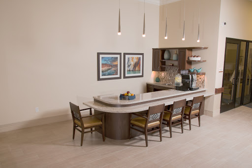 A modern kitchen dining area featuring a sleek countertop, stylish chairs, and decorative artwork.