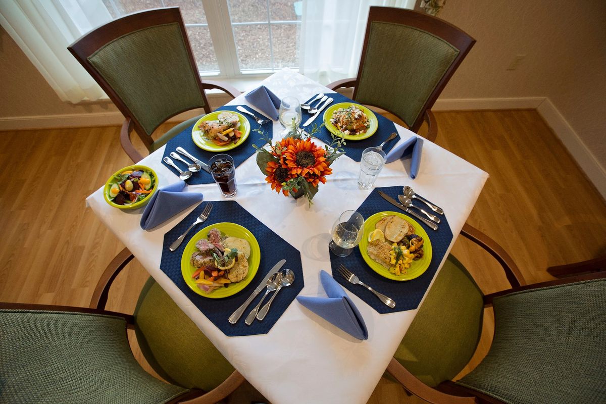 A beautifully arranged dining table set for four, featuring colorful plates and a floral centerpiece.