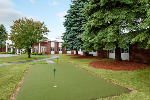 A serene putting green surrounded by lush trees and neatly landscaped grounds.