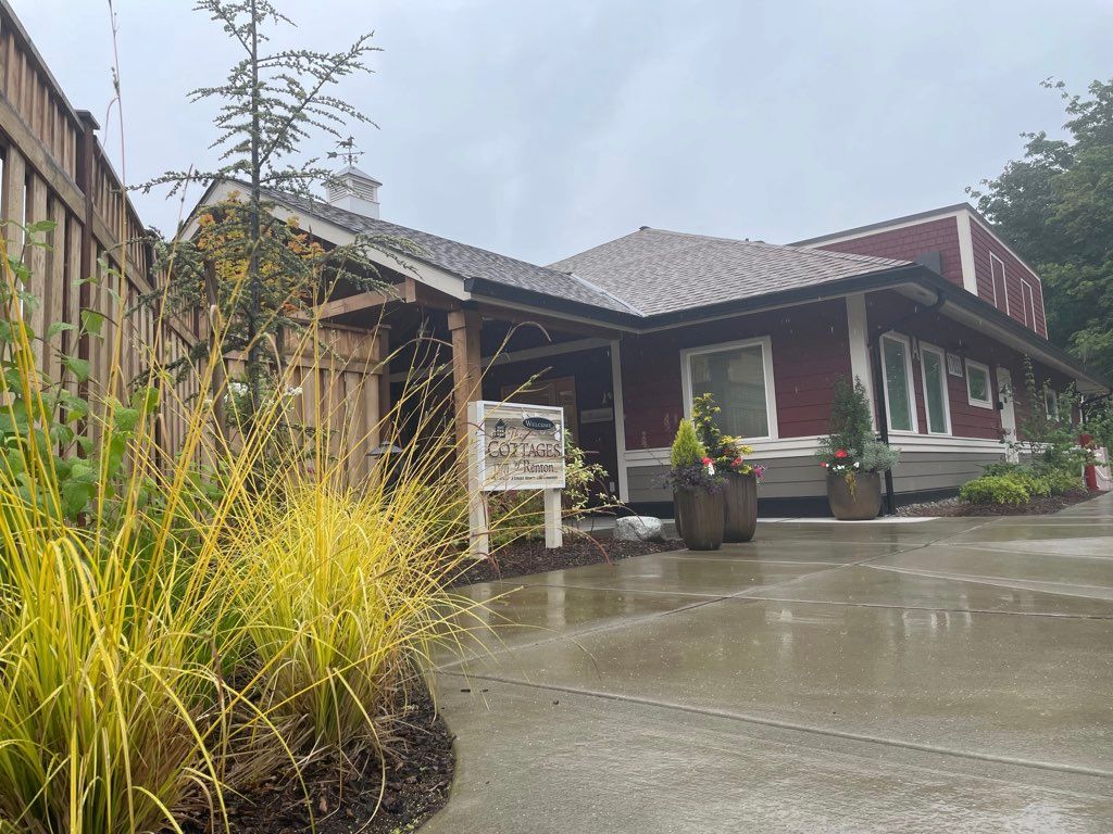 A modern house with a landscaped front yard and an overcast sky.