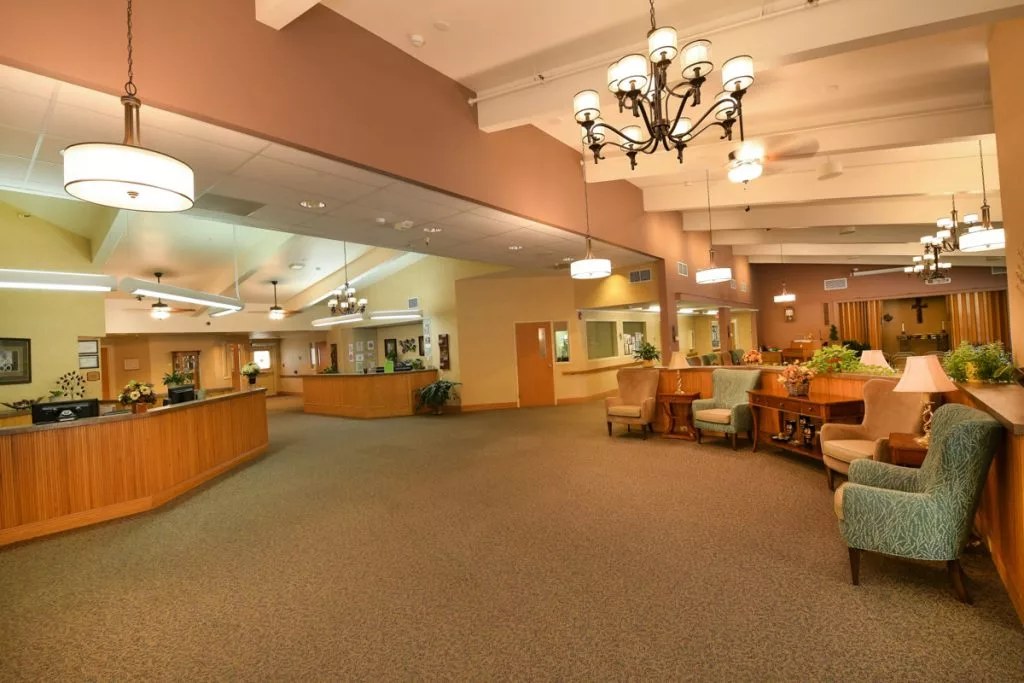 A spacious lobby area with comfortable seating and a reception desk, illuminated by chandeliers.