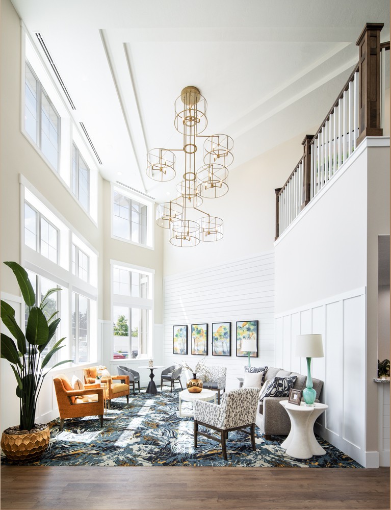 A modern living room with large windows and a striking chandelier.