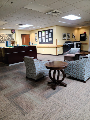 A cozy waiting area featuring stylish chairs and a wooden table, designed for comfort and relaxation.
