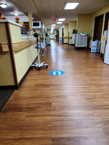 A view of a hospital hallway with wooden floors and clear directional signage on the ground.