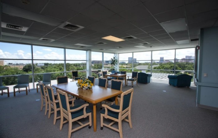 A spacious conference room with large windows offering a scenic view, equipped with a long table and several chairs.