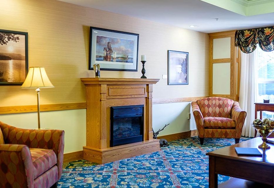 A cozy living room featuring a fireplace, armchairs, and decorative elements.