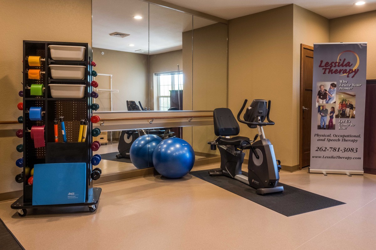A modern gym with exercise equipment including a stationary bike, exercise balls, and weights.