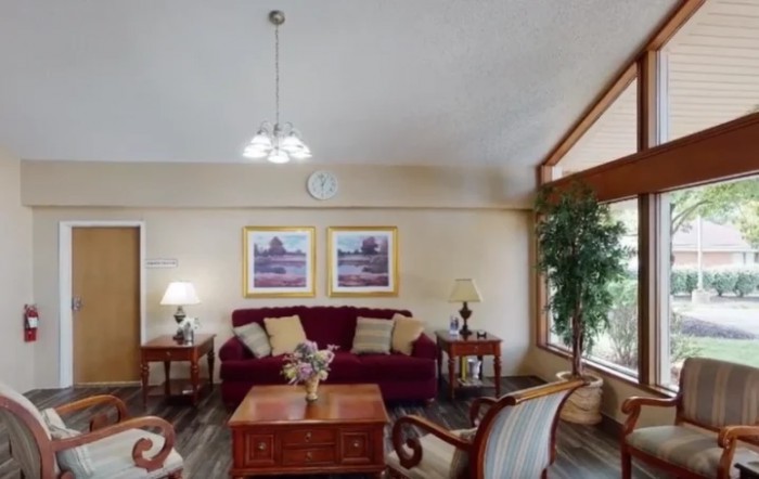 A cozy living room featuring a plush sofa, wooden coffee table, decorative lamps, and framed artwork on the wall.