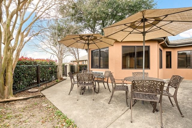 A cozy backyard patio with tables, chairs, and large umbrellas.