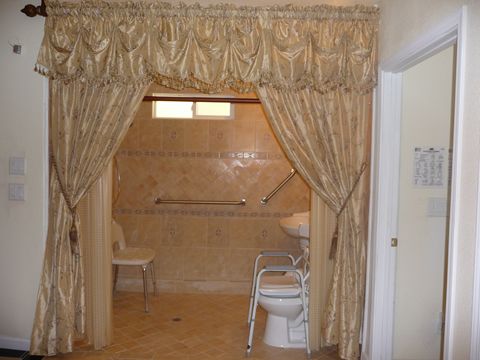 An accessible bathroom with elegant curtains and tiled walls.