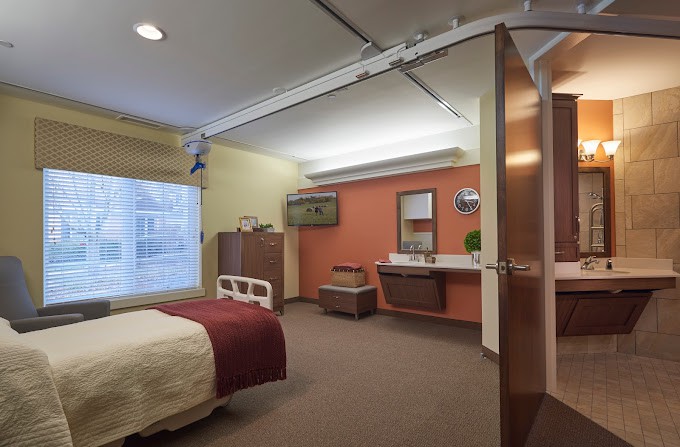 A well-furnished hospital room with a bed, window, and sink.