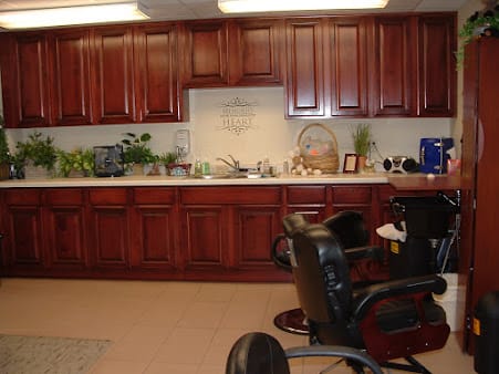 An office workspace featuring wooden cabinets and chairs, decorated with plants.