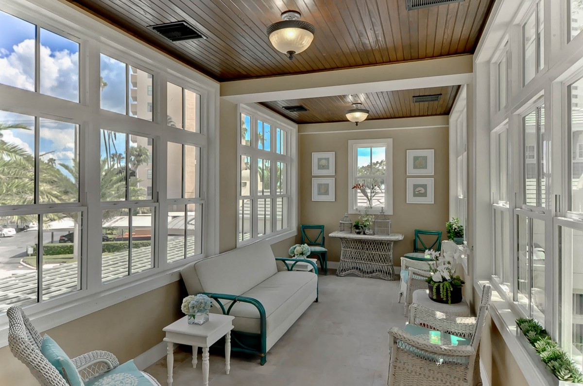A cozy sunroom with large windows and comfortable seating.