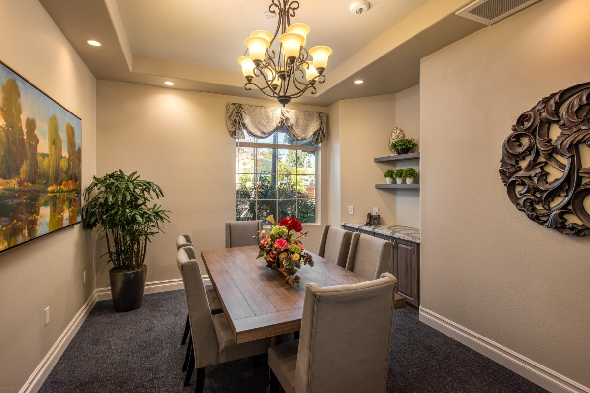 A cozy dining room with a large wooden table, elegant chandelier, and tasteful decor.