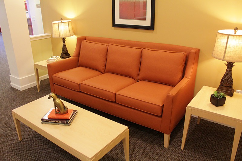 A cozy living room with an orange couch, a lamp, and a coffee table.