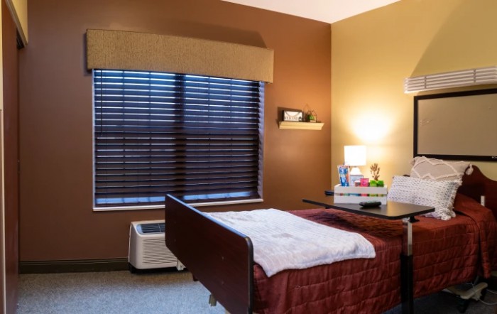 A cozy room with a hospital bed, warm lighting, and decorative elements on the nightstand.