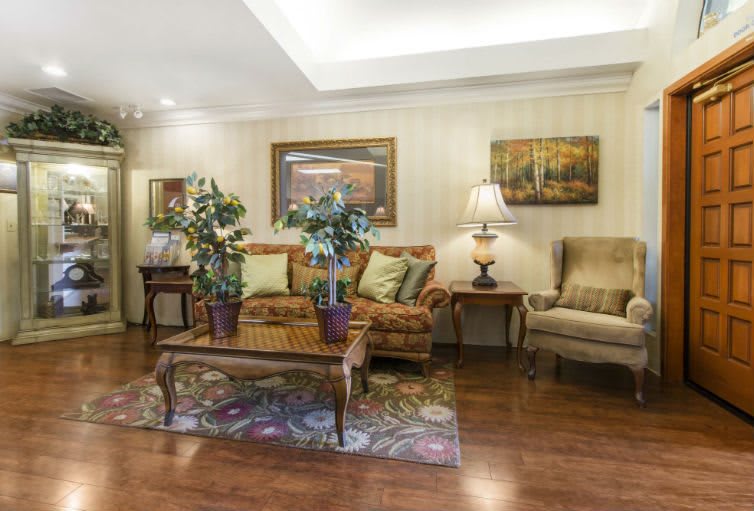 A cozy living room with a sofa, armchair, coffee table, and decorative elements such as plants and artwork.