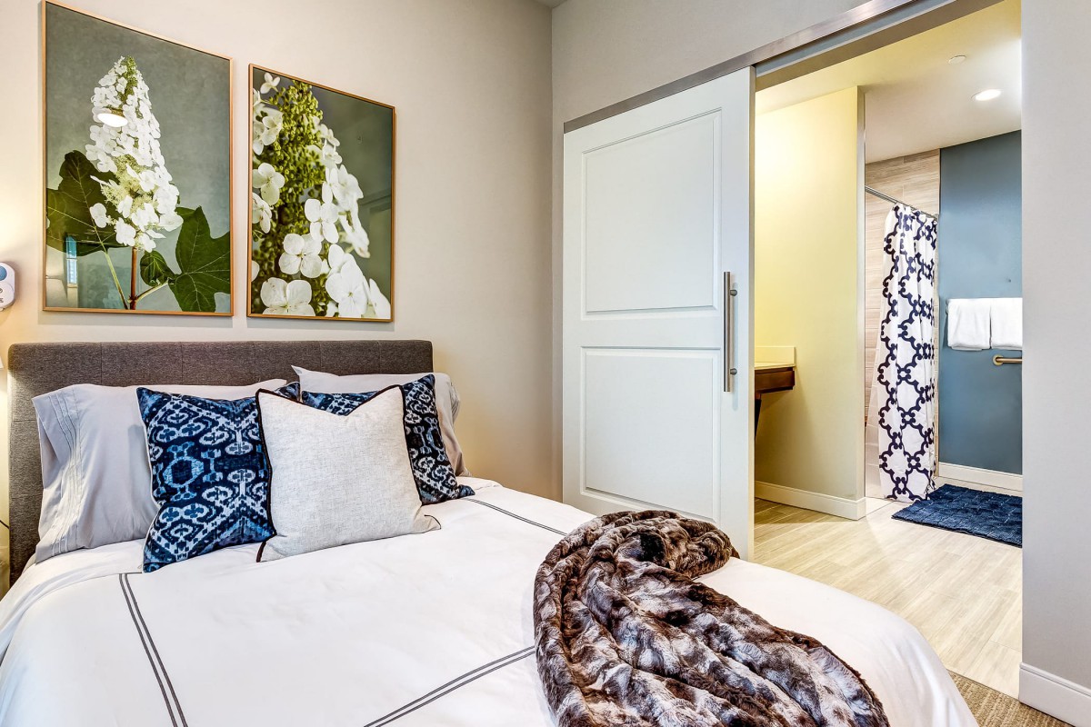 A cozy bedroom with modern decor and artwork above the bed.