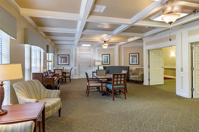 A spacious lounge area with tables, chairs, and decorative paintings.