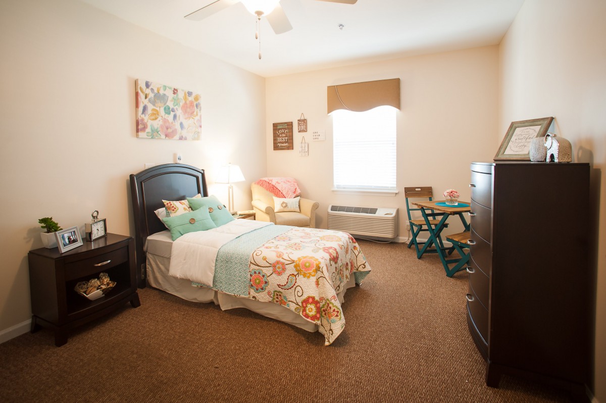 A cozy bedroom with a single bed, colorful bedding, and a small desk by the window.