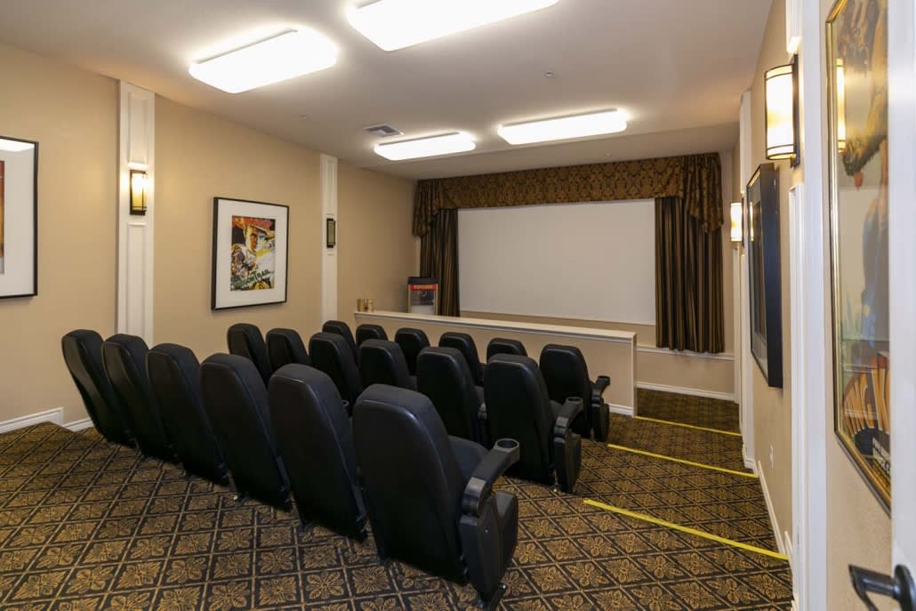 A cozy home theater with rows of comfortable seating facing a large projection screen.