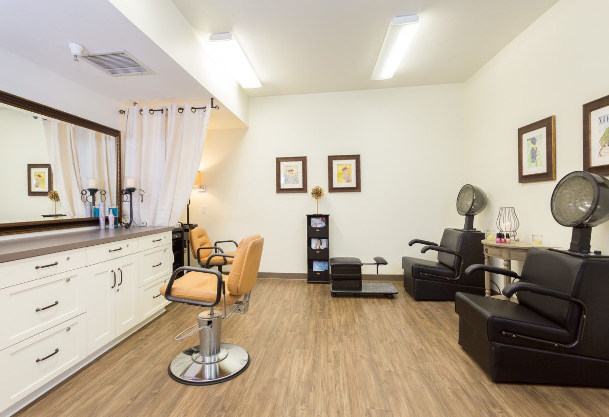A modern hair salon interior featuring styling chairs, mirrors, and hairdressing equipment on a wooden floor.