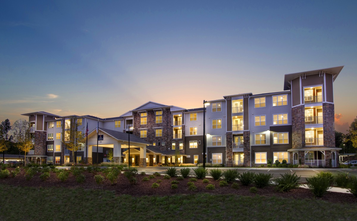 A modern residential building illuminated at dusk.