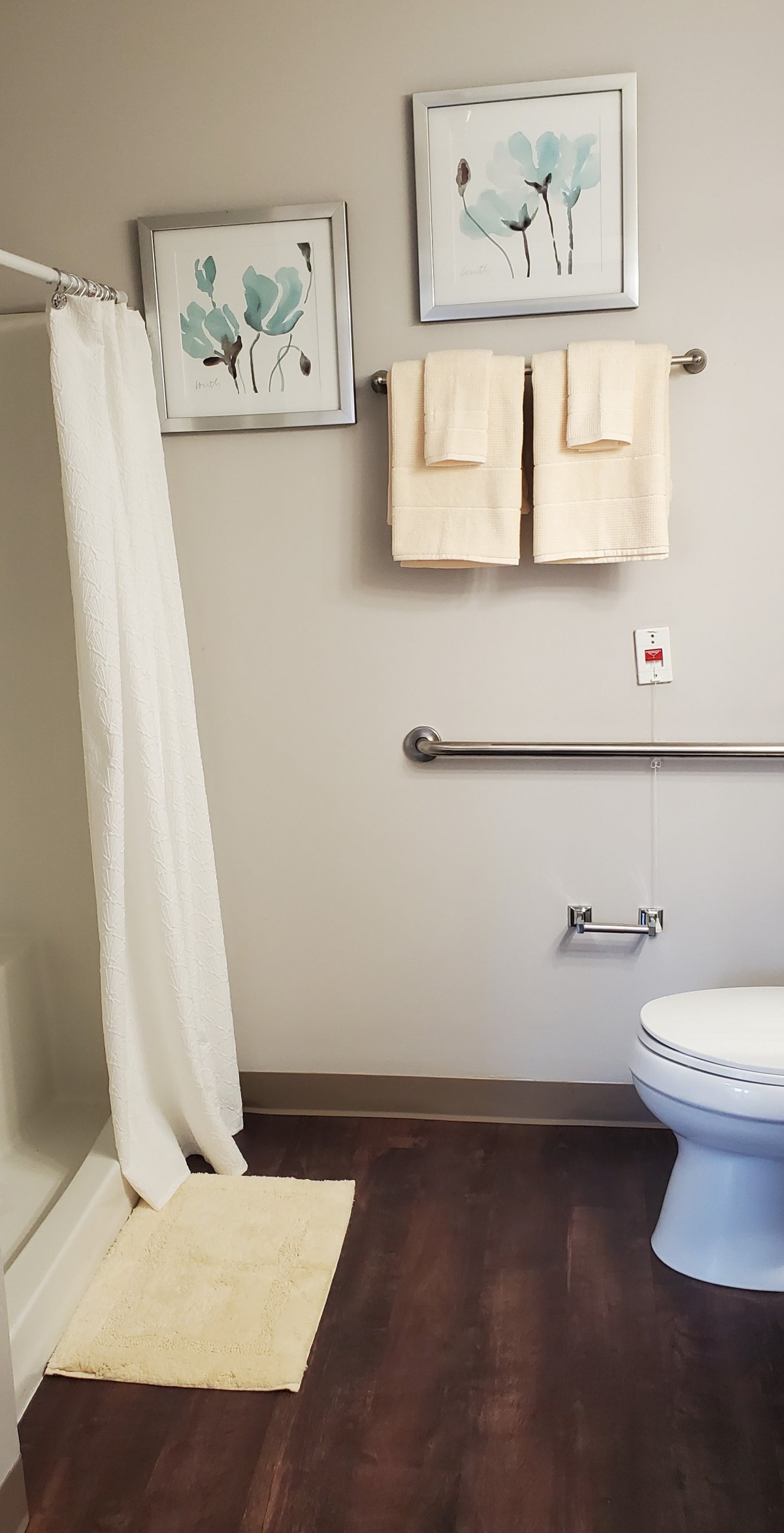 A clean and well-organized bathroom with a shower curtain, towels, and handrail.