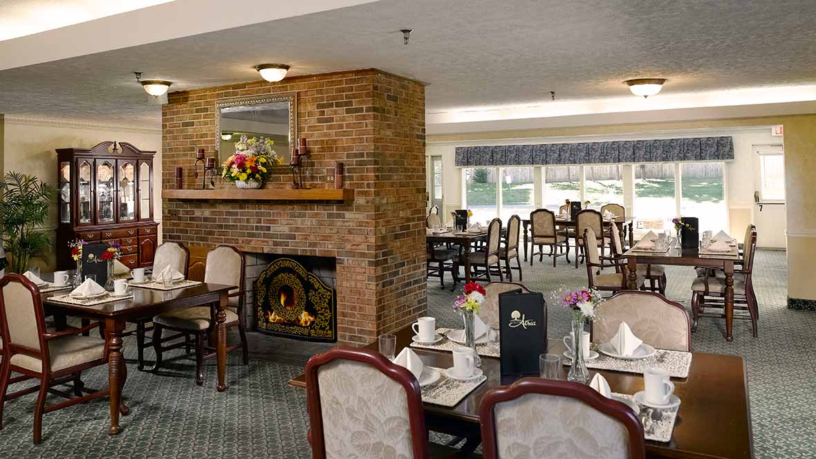 Cozy dining area with a fireplace and elegantly set tables in a restaurant.