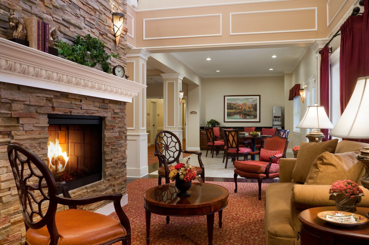 A cozy living room featuring a stone fireplace, elegant furniture, and warm decor.