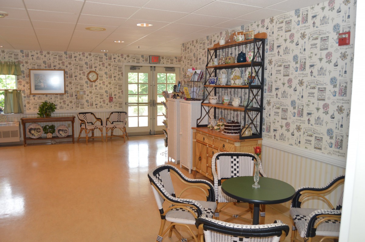 A cozy cafe interior with tables, chairs, and decorative shelves.